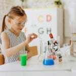 Dziewczynka robi doświadczenie chemiczne przy domowym stoliku badawczym