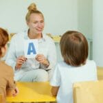 Nauczycielka pokazuje literę przedszkolakom podczas zajęć w klasie