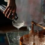 Barman przelewa koktajl z shakera do kieliszka w domowym barze