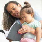 Mama czytająca interaktywną książkę z małą córką w domu