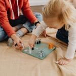 Mama i córka grają w planszówkę w domu, ucząc się współpracy