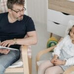 Tata czyta córce książkę interaktywną podczas wspólnej zabawy