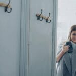 Uśmiechnięta kobieta trzyma płaszcz w przymierzalni butiku