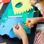Dziecko wycina kolorowy papier nożyczkami podczas pracy plastycznej