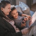 Mama czyta książkę z uśmiechniętym synem w domowym zaciszu