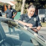 Policjantka wypisuje mandat za wykroczenie drogowe na parkingu