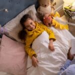 Uśmiechnięte dziecko słucha bajki na dobranoc w przytulnym pokoju pełnym zabawek