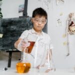 Dziecko w goglach robi kolorowy eksperyment chemiczny w szkolnej klasie